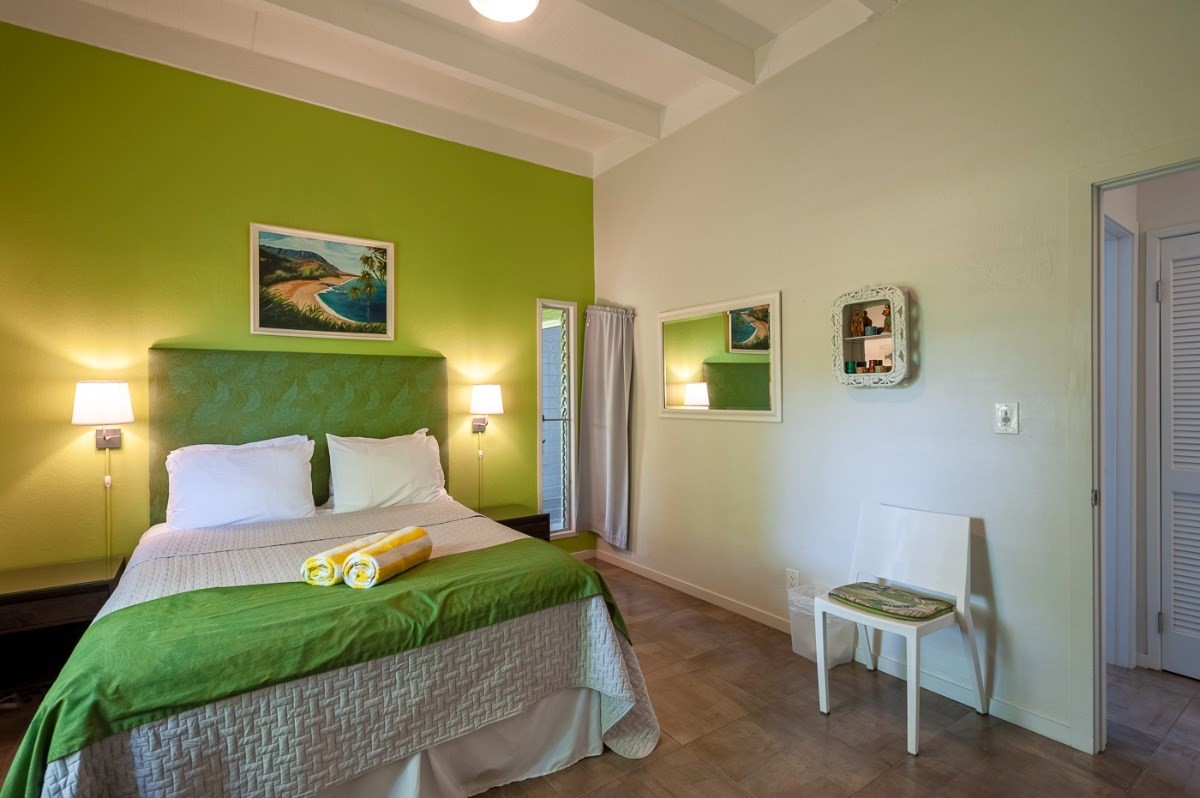 3880 Wyllie Road, Unit 1A Princeville, HI 96722 - Photo 18 of 22 a bedroom with a bed and a chair with potted plant