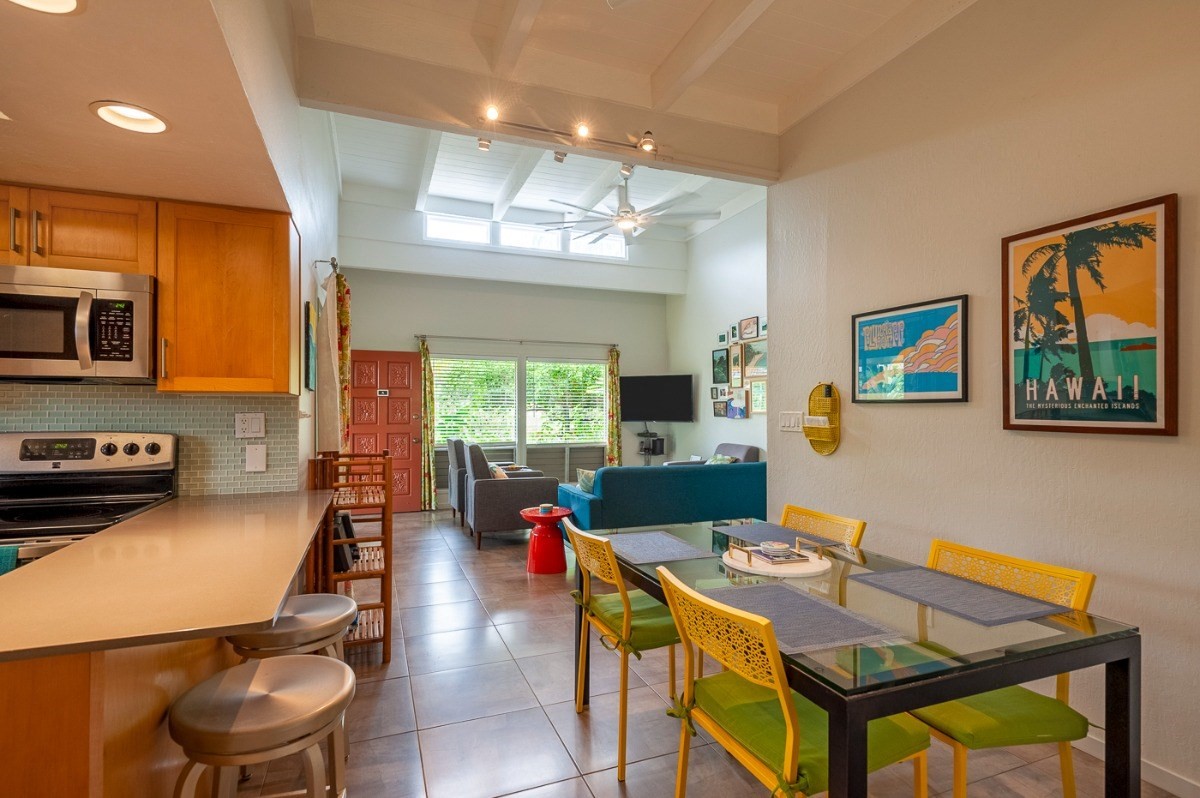 3880 Wyllie Road, Unit 1A Princeville, HI 96722 - Photo 5 of 22 a living room with furniture a flat screen tv and a dining table