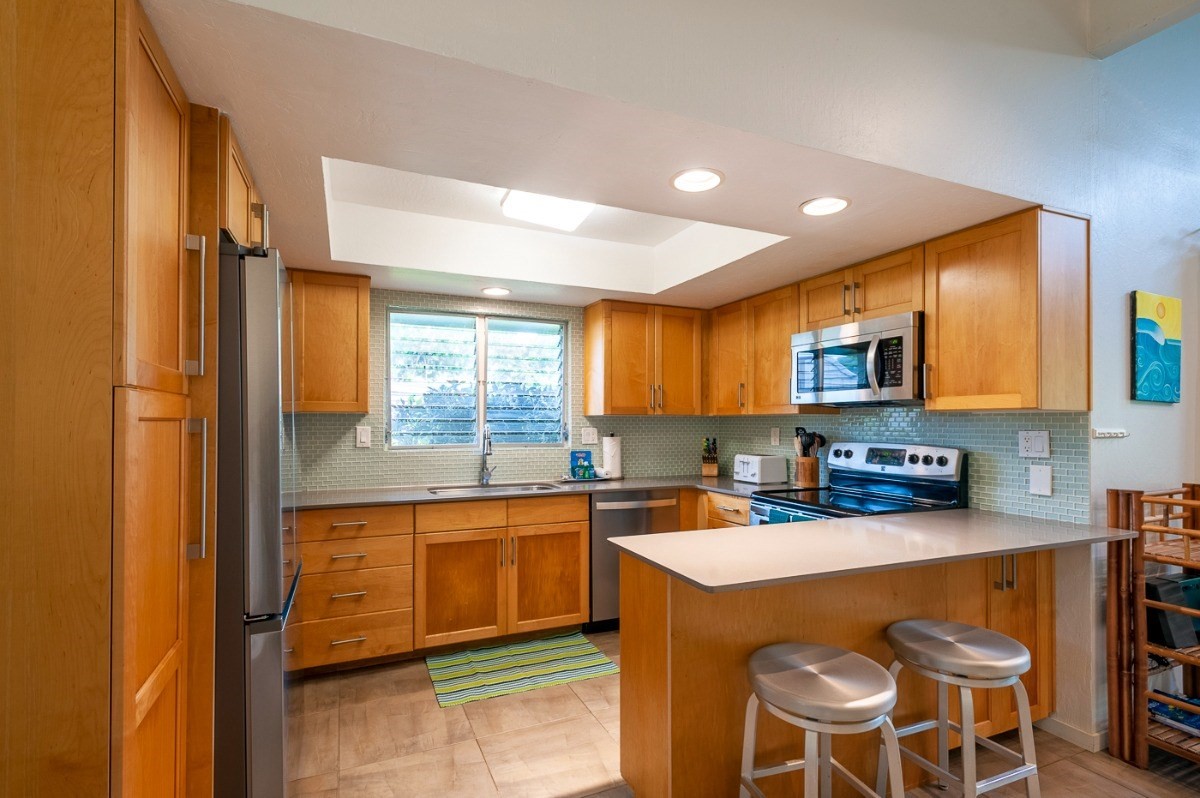 3880 Wyllie Road, Unit 1A Princeville, HI 96722 - Photo 6 of 22 a kitchen with a sink a stove a refrigerator cabinets and dining table