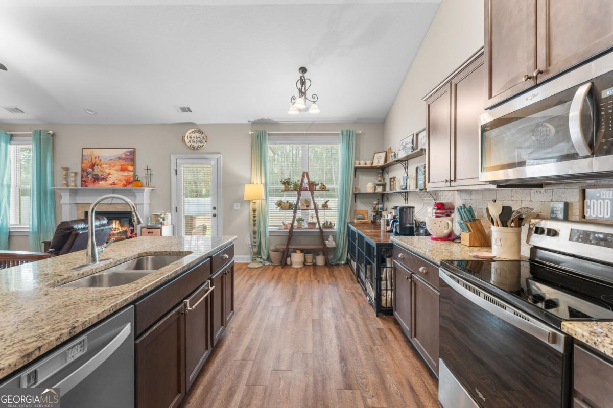 161 Laguna Way Savannah, GA 31405 - Photo 16 of 33 a kitchen with stainless steel appliances granite countertop a stove top oven a sink dishwasher a dining table and chairs with wooden floor