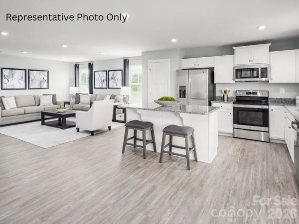 a living room with stainless steel appliances granite countertop furniture wooden floor and a view of kitchen