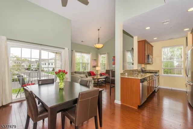 a kitchen with stainless steel appliances granite countertop a stove a sink dishwasher a dining table and chairs with wooden floor