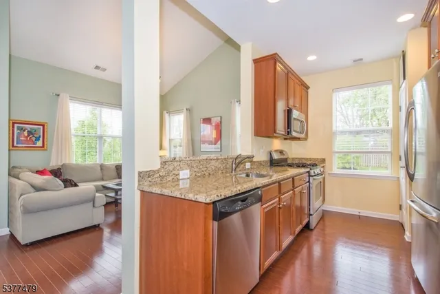 a open kitchen with stainless steel appliances granite countertop a sink and a large window