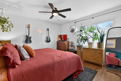 a bedroom with a bed a dresser and a large window