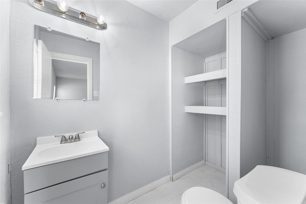 612 East 8th Street Kemp, TX 75143 - Photo 18 of 25 Bathroom featuring a light gray vanity with a built-in sink, wall-mounted mirror, and overhead light bar