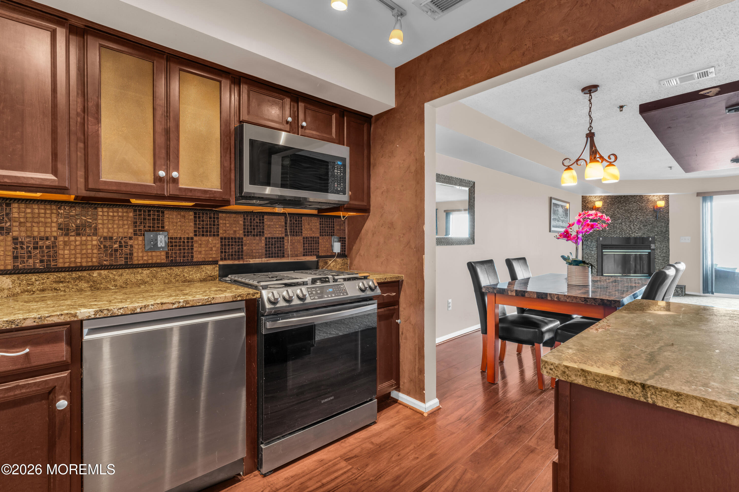 135 1st Street, Unit 1E Keyport, NJ 07735 - Photo 23 of 40 a kitchen with stainless steel appliances granite countertop a stove top oven a sink dishwasher a dining table and chairs with wooden floor