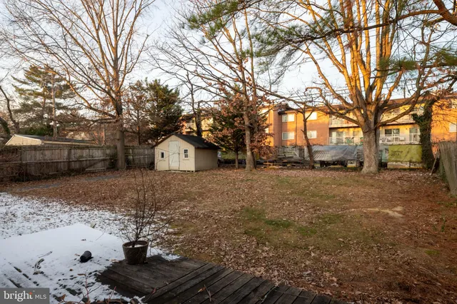 a view of backyard with large trees and wooden fence