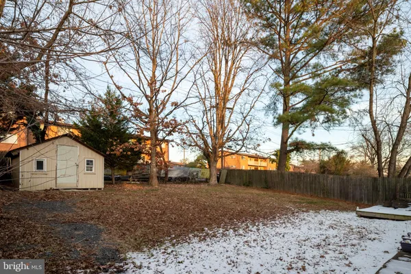 a backyard of a house with large trees and a wooden fence