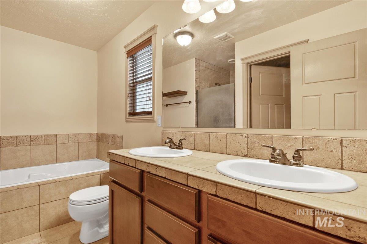 1513 Fairway Street Middleton, ID 83644 - Photo 11 of 20 Full bathroom featuring double vanity, a bath, a textured ceiling, and tiled shower