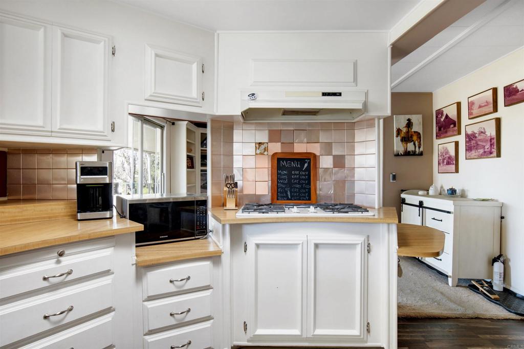 18218 Paradise Mountain Road Valley Center, CA 92082 - Photo 11 of 53 a kitchen with granite countertop a stove and white cabinets