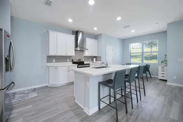 a kitchen with stainless steel appliances granite countertop a stove a sink a refrigerator and a dining table with wooden floor