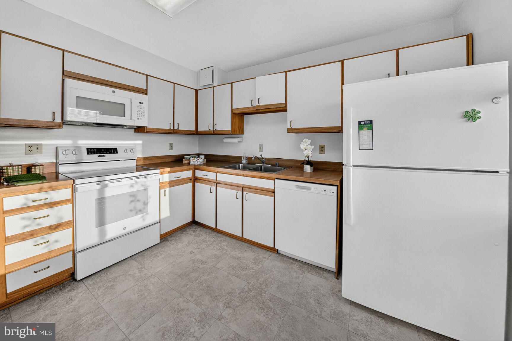15107 Interlachen Drive, Unit 21025 Silver Spring, MD 20906 - Photo 15 of 38 a white kitchen with granite countertop stainless steel appliances and white cabinets