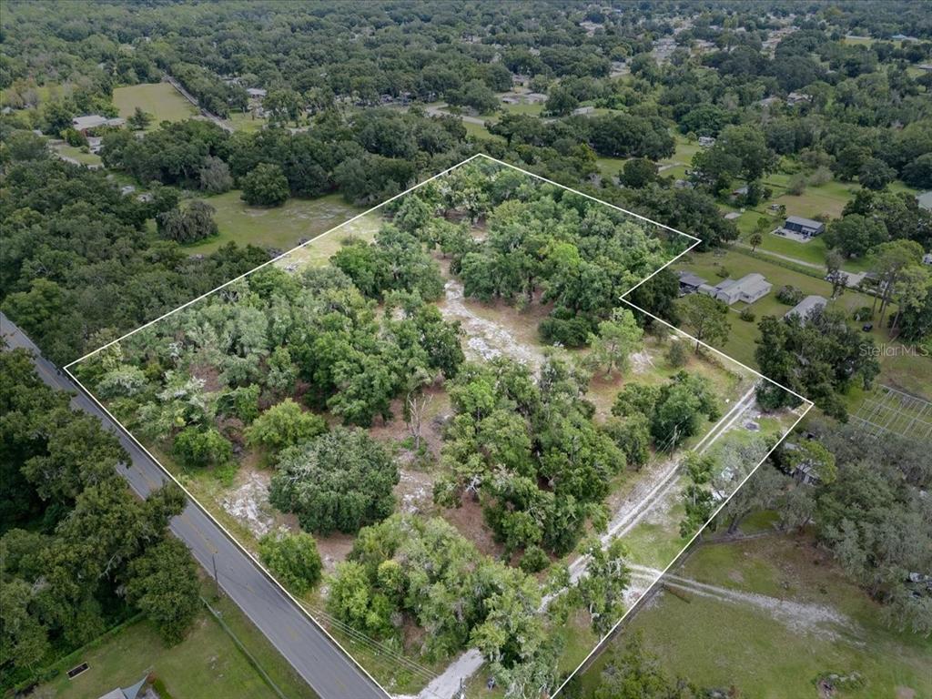 an aerial view of residential houses with outdoor space and trees