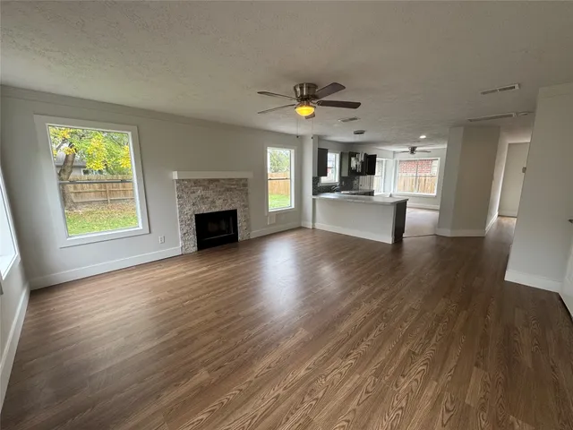 an empty room with fireplace wooden floor and windows