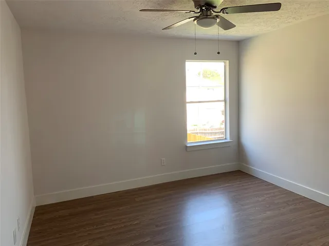 an empty room with a window and a ceiling fan