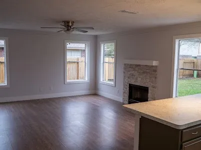 a view of an empty room with wooden floor fireplace and a window