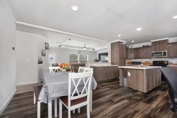 a kitchen with stainless steel appliances granite countertop a sink a stove a refrigerator a dining table and chairs