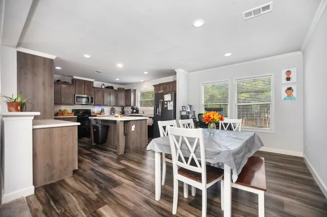 a view of a dining room with furniture a rug and kitchen view