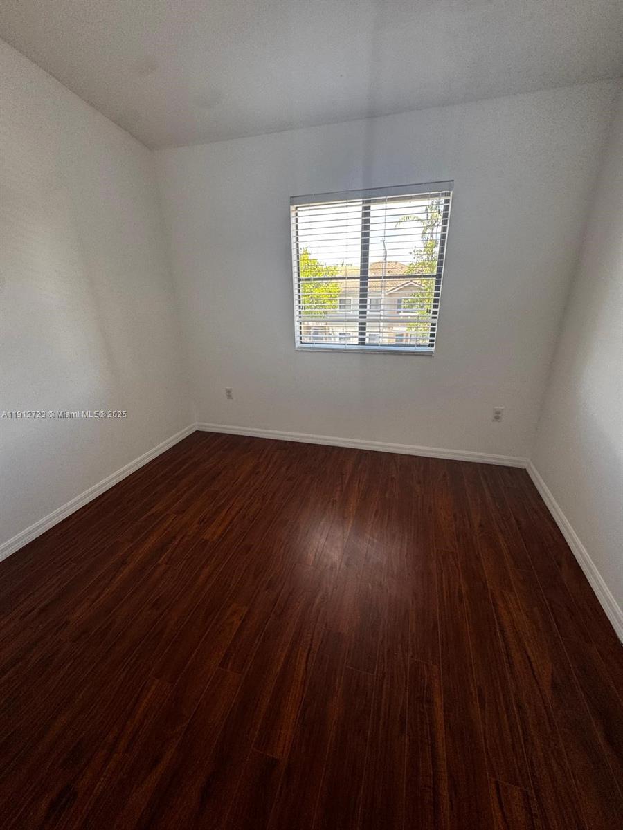 22621 Southwest 88th Place, Unit 3028 Cutler Bay, FL 33190 - Photo 11 of 18 a view of an empty room with wooden floor and a window