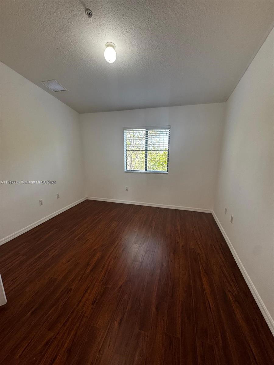 22621 Southwest 88th Place, Unit 3028 Cutler Bay, FL 33190 - Photo 12 of 18 an empty room with wooden floor and windows