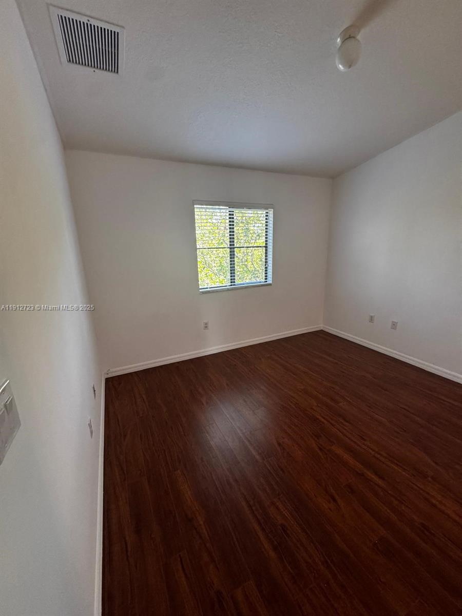 22621 Southwest 88th Place, Unit 3028 Cutler Bay, FL 33190 - Photo 13 of 18 an empty room with wooden floor and windows