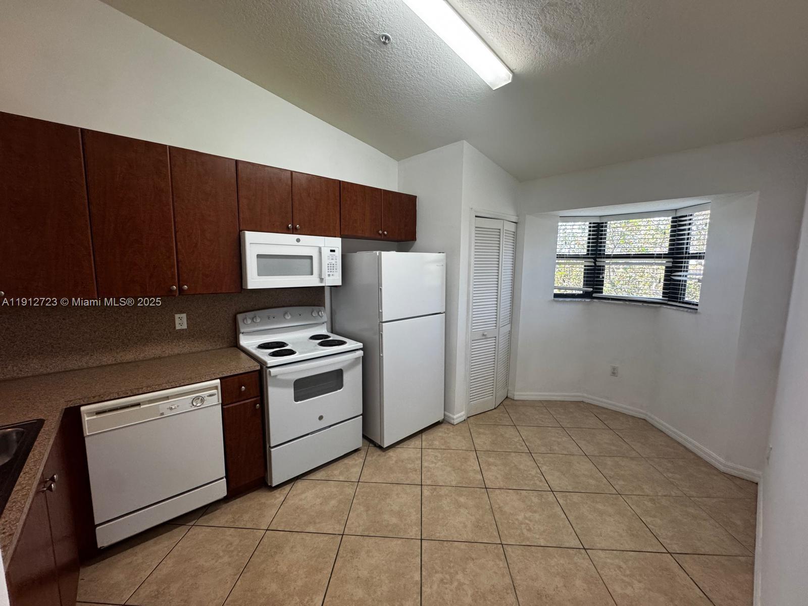 22621 Southwest 88th Place, Unit 3028 Cutler Bay, FL 33190 - Photo 9 of 18 a kitchen with a stove a sink and a refrigerator