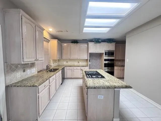 a kitchen with granite countertop kitchen island stainless steel appliances a sink stove and cabinets