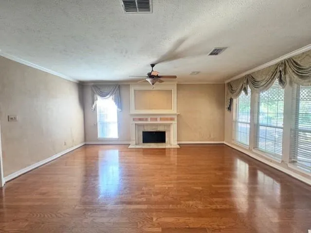 wooden floor fireplace and windows in an empty room