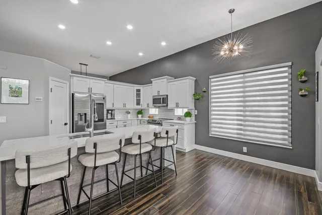 a large kitchen with cabinets chairs and wooden floor