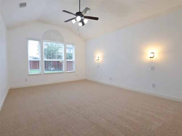 an empty room with chandelier fan and windows