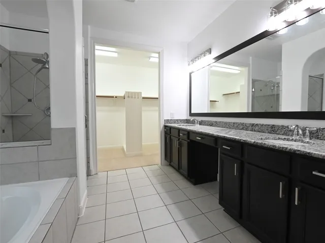 a spacious bathroom with a granite countertop sink a mirror and a bathtub