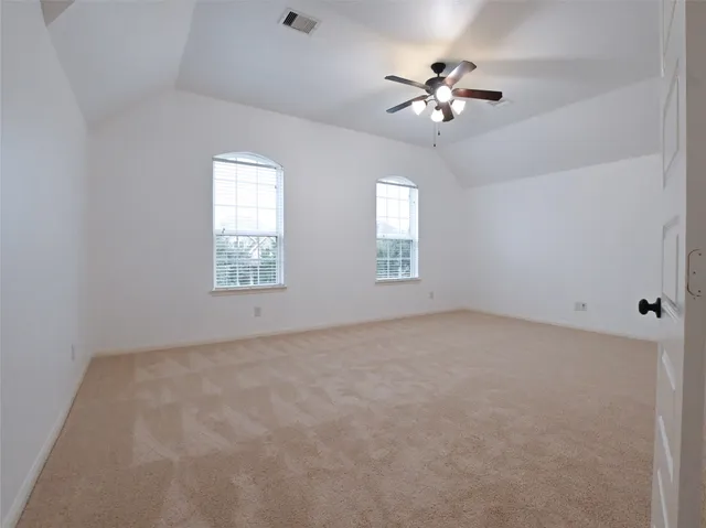 an empty room with windows and chandelier fan