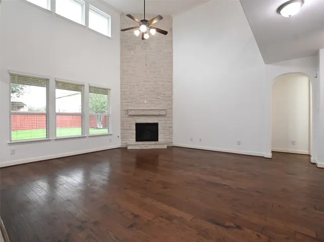 an empty room with wooden floor fan and windows