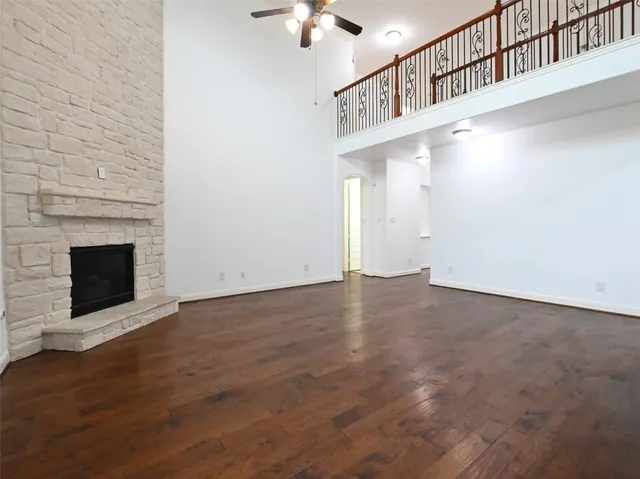 a view of an empty room with wooden floor a fireplace and a window