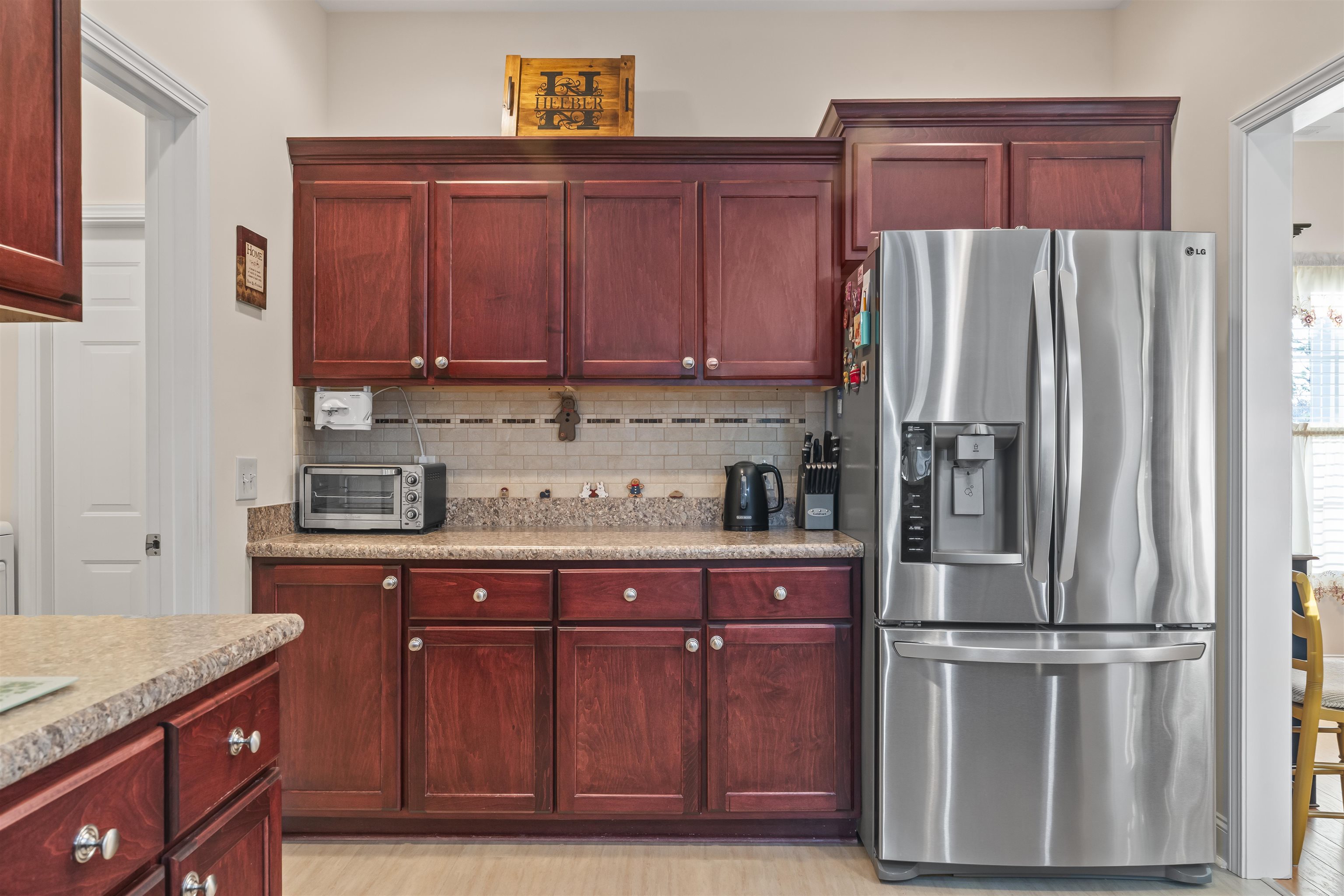 830 Payne Court Conway, SC 29526 - Photo 12 of 38 Kitchen with dark brown cabinets, stainless steel fridge with ice dispenser, backsplash, and light stone countertops