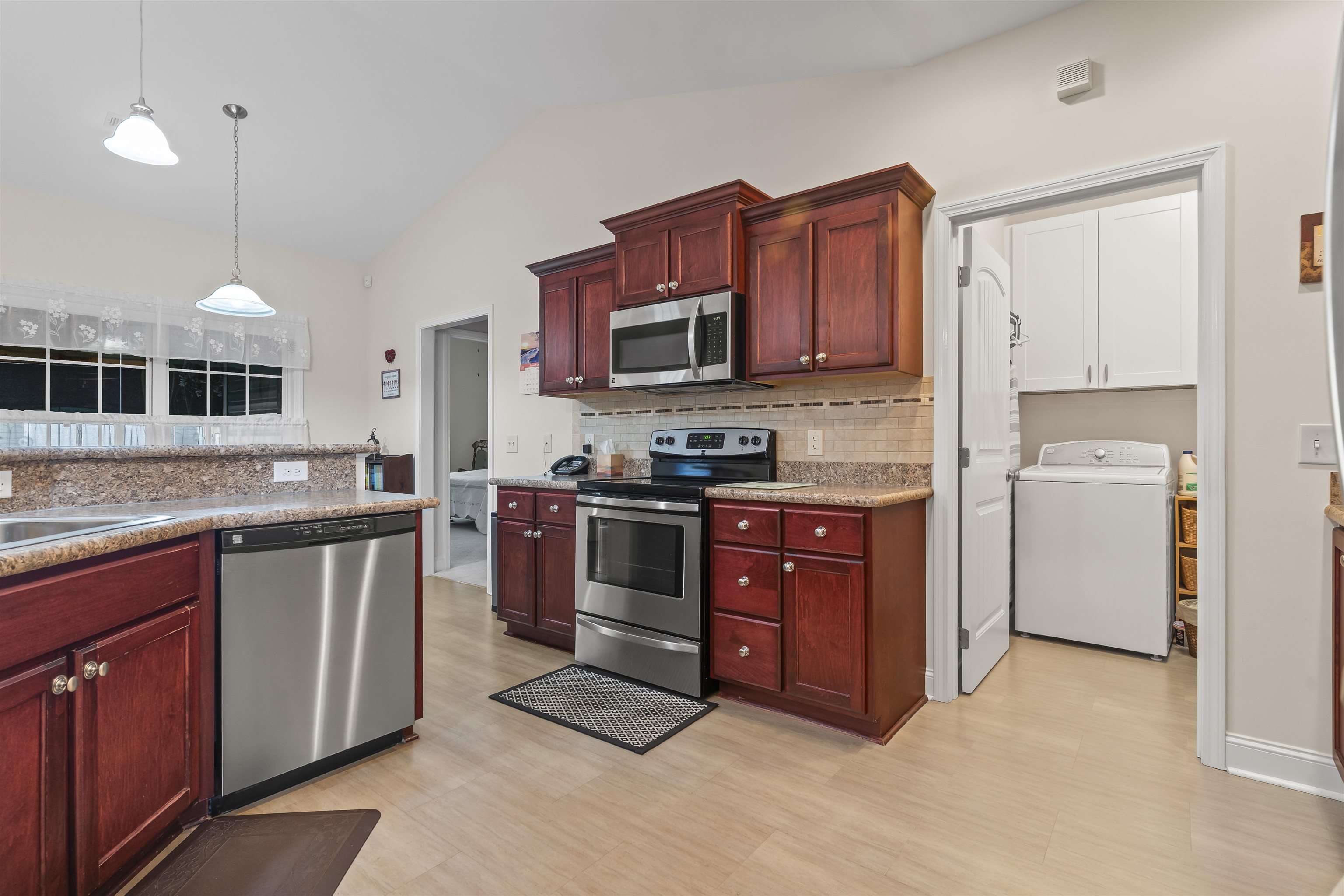 830 Payne Court Conway, SC 29526 - Photo 13 of 38 Kitchen featuring reddish brown cabinets, stainless steel appliances, washer / dryer, vaulted ceiling, and pendant lighting