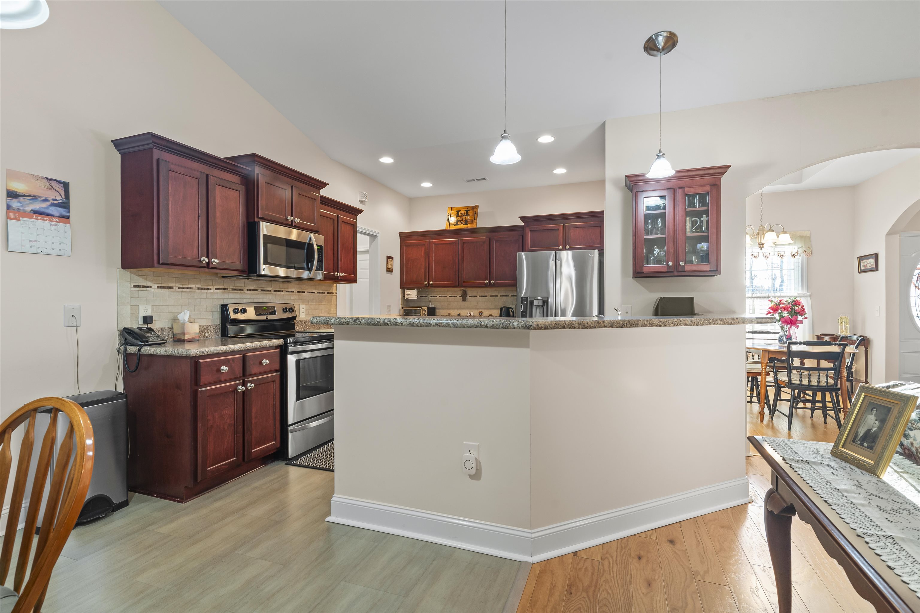 830 Payne Court Conway, SC 29526 - Photo 9 of 38 Kitchen with reddish brown cabinets, stainless steel appliances, light stone counters, arched walkways, and hanging light fixtures