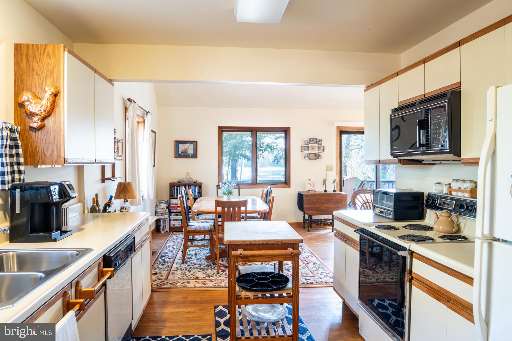 162 Youcomico Drive Lancaster, VA 22503 - Photo 11 of 31 a open kitchen with stainless steel appliances granite countertop a stove top oven a sink dishwasher a dining table and chairs with wooden floor