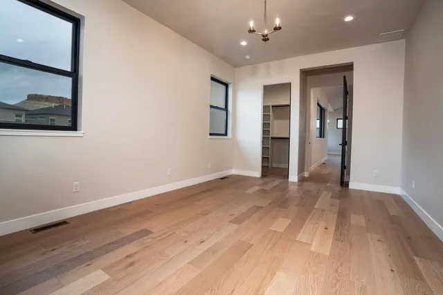 a view of an empty room with wooden floor and closet