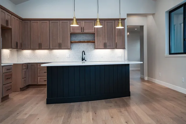 a kitchen with stainless steel appliances granite countertop a sink a microwave a refrigerator and wooden cabinets