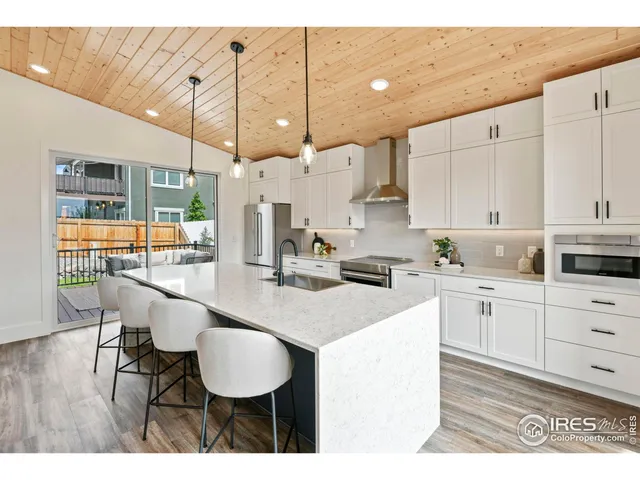 a kitchen with stainless steel appliances kitchen island granite countertop a table chairs and a white cabinets