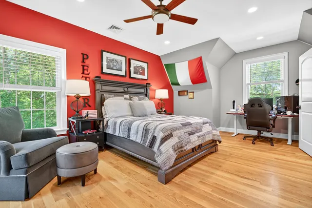 a bedroom with a bed and dresser with wooden floor