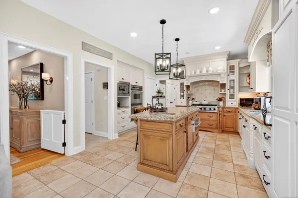 a large kitchen with stainless steel appliances kitchen island granite countertop a refrigerator and a stove top oven
