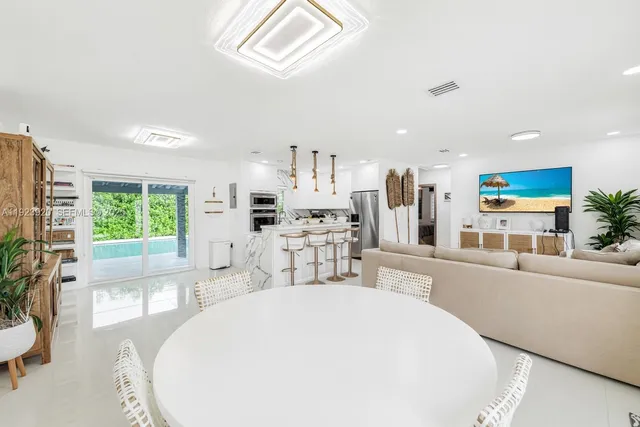 a living room with furniture a large window and stainless steel appliances