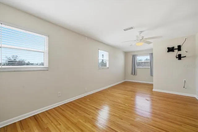 a view of empty room with wooden floor and fan
