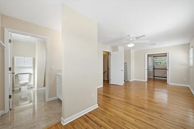a view of an empty room with wooden floor and a kitchen