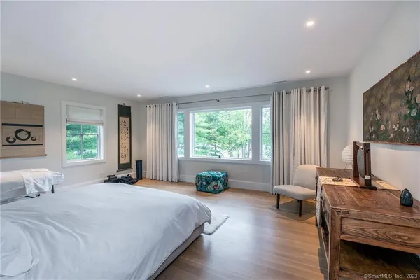 a bedroom with a bed a large window and wooden floor