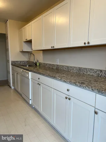 a kitchen with granite countertop white cabinets and sink