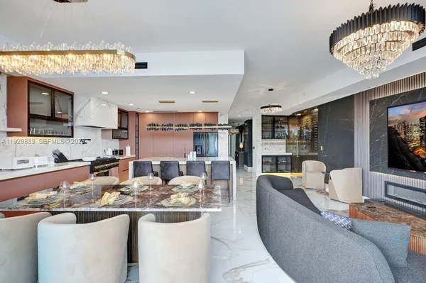a large kitchen with stainless steel appliances kitchen island granite countertop a refrigerator a stove a sink dishwasher with a dining table and chairs with wooden floor