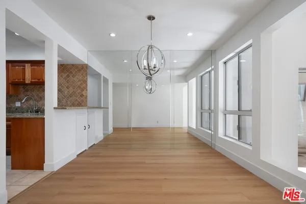 a view of a hallway with wooden floor and chandelier